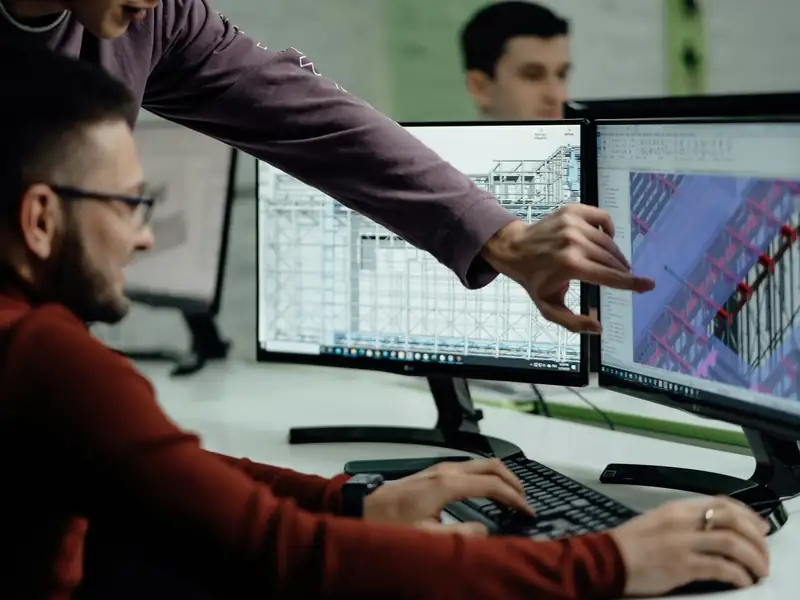 Engineers reviewing technical designs together on twin monitors