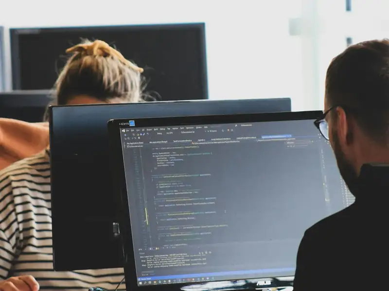 Software engineers reviewing code together on large monitors in a bright office